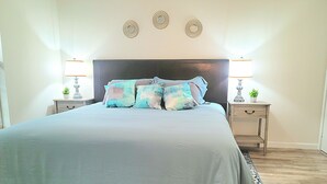 A neatly made bed with a patterned rug, two bedside tables with lamps, and decorative wall mirrors.