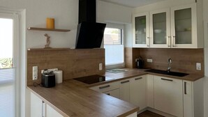 A modern kitchen with a wooden countertop, white cabinets, and a black range hood.