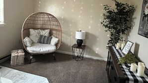 A cozy room with a round wicker chair, a small table with candles, and a potted plant. - Country Getaway, 2- bedroom, Jacuzzi, fire ring (Woodbury)
