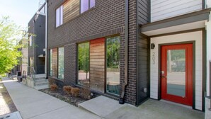 A modern two-story apartment building with a brick facade, large windows, and a red door. - Midtown Skyline Retreat | Rooftop Deck | Game Room (Nashville)