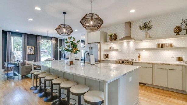 A modern kitchen with a large island, bar stools, pendant lighting, and a view of the outdoors. - Midtown Skyline Retreat | Rooftop Deck | Game Room (Nashville)