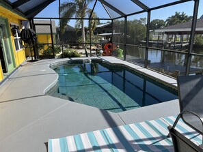 An indoor swimming pool with clear water, surrounded by a covered area with large windows. - Florida waterfront home with pool and use of kayaks (Ruskin)