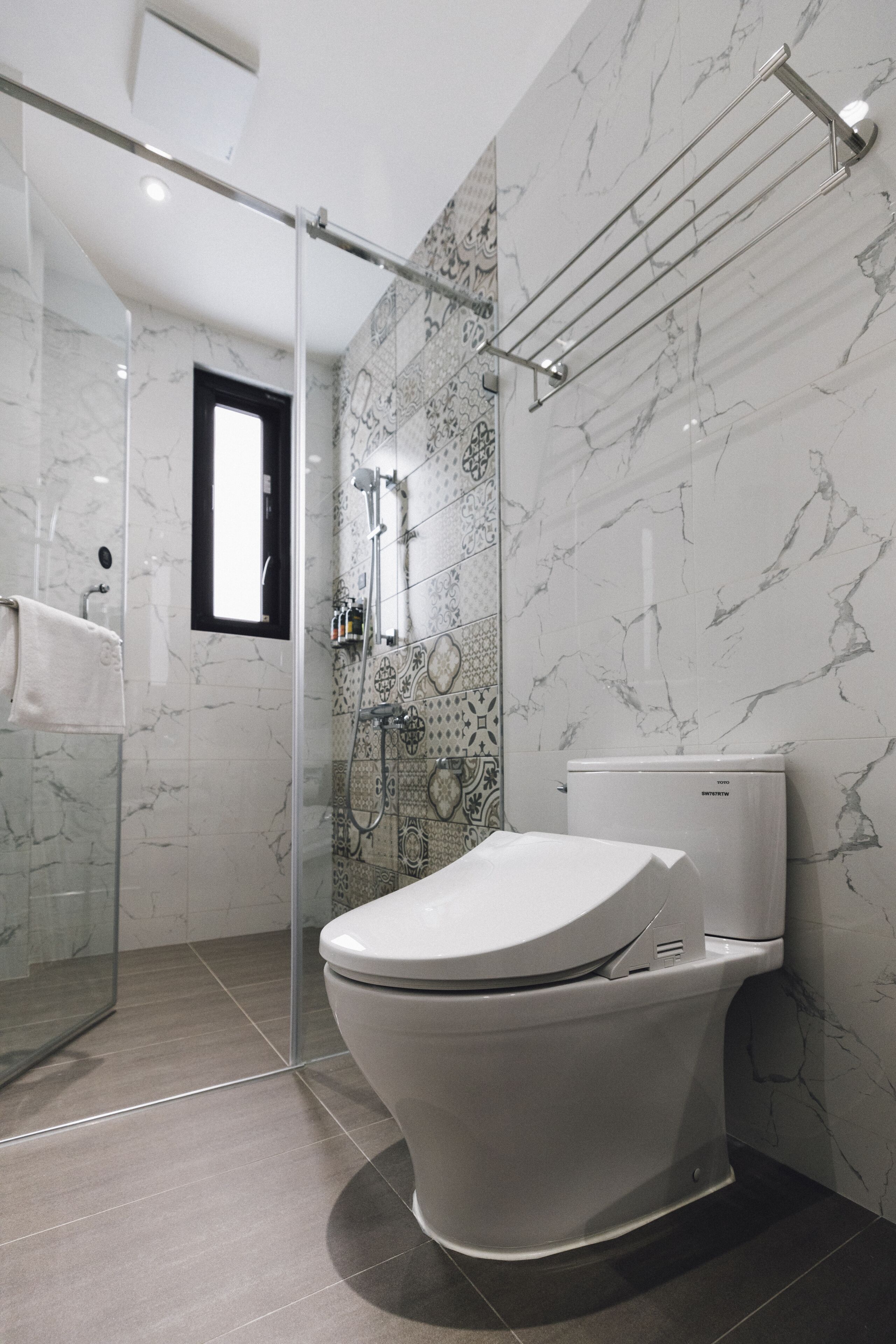 Ein modernes Badezimmer mit Duschkabine aus Glas, Toilette und Handtuchhalter.