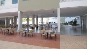 A spacious indoor area with multiple tables and chairs, large windows, and a modern architectural design. - RIVIERA PARK - JC TEMPORADA (Caldas Novas)