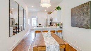 A modern kitchen with white cabinets, a central island, and a hanging pendant light. - Stylish Rooftop Haven | Sleeps 12 Comfortably (Nashville)