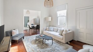 Una sala moderna con un sofá, una mesa de centro y un comedor al fondo.
