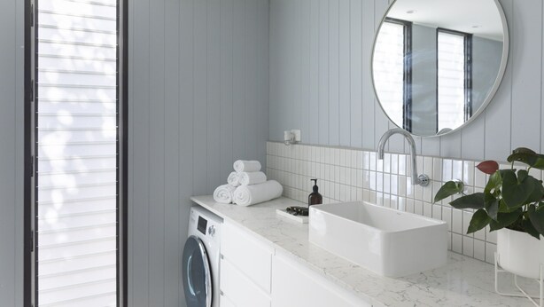 Un baño moderno con lavadora integrada, lavamanos y espejo.