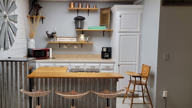Une cuisine avec un îlot central en bois, des meubles blancs et une horloge décorative.