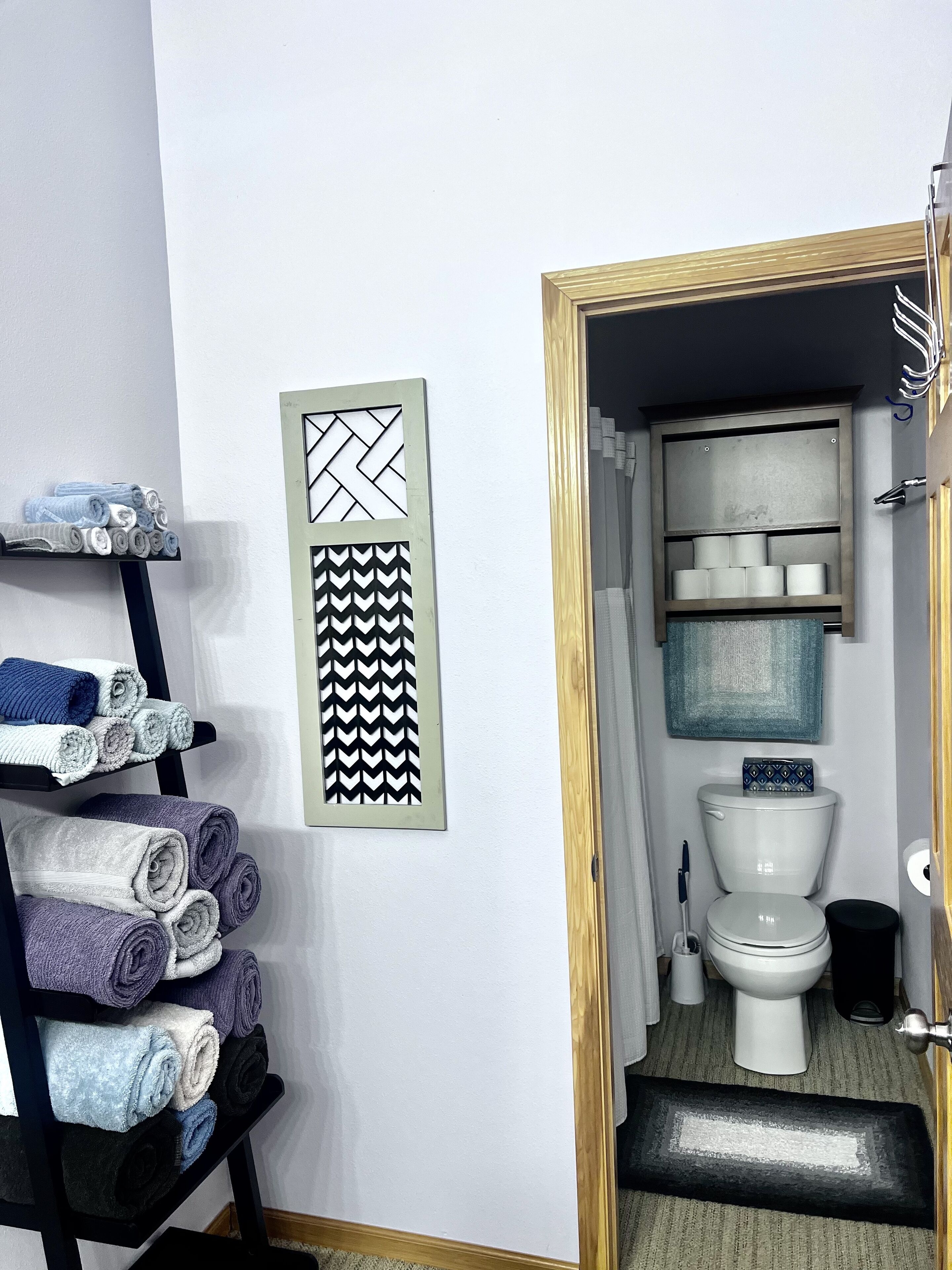 Un baño con un inodoro, un perchero con toallas y un toallero de pared.