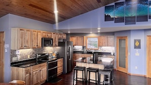 A modern kitchen with wooden cabinets, stainless steel appliances, and a large island with bar stools. - River Run Ridge- HOT TUB- sleeps 14 (Lynxville)