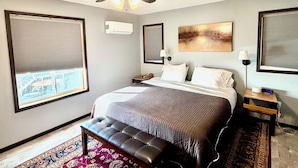 A hotel room with a bed, a ceiling fan, a large window with blinds, a bedside table with a lamp, and a rug. - River Run Ridge- HOT TUB- sleeps 14 (Lynxville)
