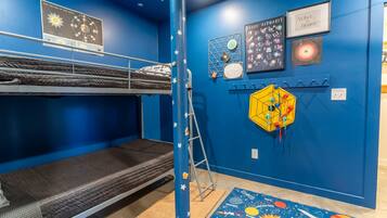 Una habitación con literas, una escalera, decoración temática del espacio y un techo estrellado.