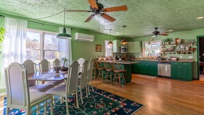 A spacious kitchen with green cabinets, a dining area with a patterned rug, and ceiling fans. -     Peaceful Mountain Retreat: Private Creek, Fireflies & Family Fun (Sparta)