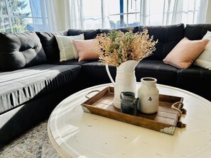 A living room with a black leather sofa, a white coffee table, and a tray with decorative items. - Remodeled, cozy, vintage charmer (Albany)