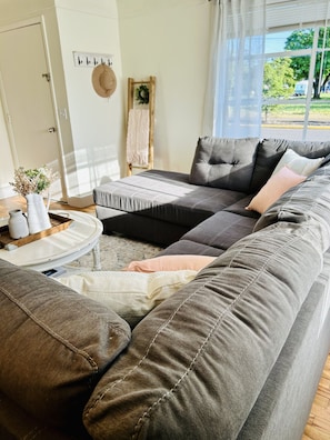 A modern living room with a sectional sofa, a coffee table, and a decorative wreath on the wall.