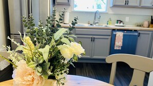 A kitchen with white cabinets, a stainless steel refrigerator, and a window. - Remodeled, cozy, vintage charmer (Albany)