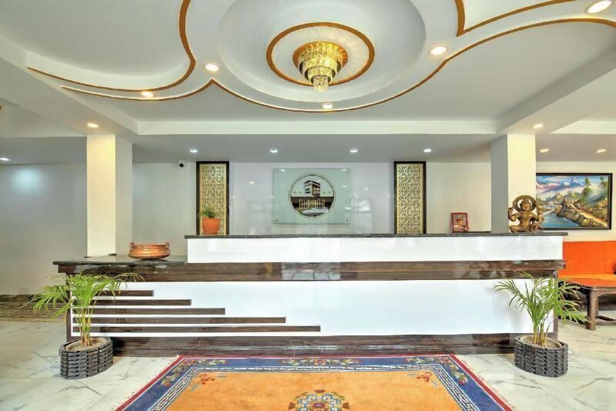 A reception desk with a modern design, a chandelier, and a framed logo.