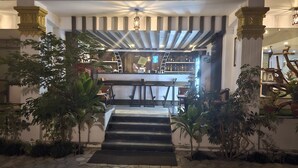Una zona de bar con mostrador, taburetes y una escalera que sube a un nivel superior.