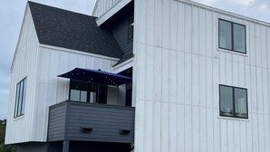 Une maison moderne à deux étages, dotée d’un garage, d’un patio couvert et d’un petit jardin.