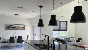 Une cuisine moderne dotée d’un îlot central, de luminaires suspendus et d’un coin repas avec des chaises et une table.