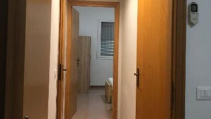 A narrow hallway with wooden doors and a light fixture on the ceiling.