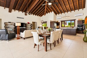 A spacious living area with a dining table set for six, a sofa, and a kitchen with a large island.