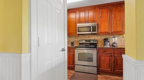 A kitchen with wooden cabinets, a microwave, a stove, and a coffee maker.