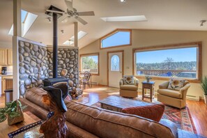 A spacious living room with a stone wall, a fireplace, a large sofa, and a view of the outdoors.