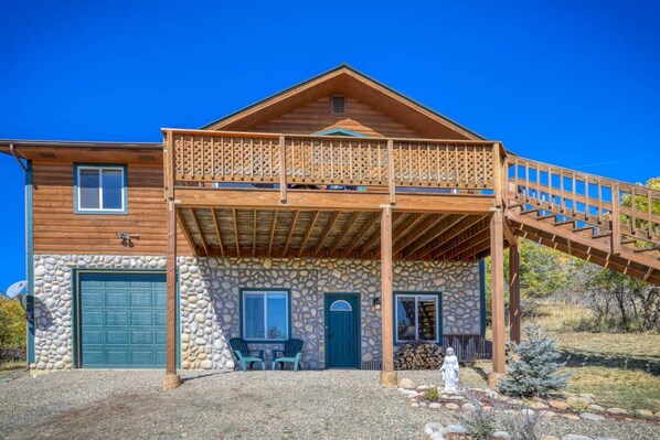 A wooden house with a stone facade, a balcony, and a covered porch.