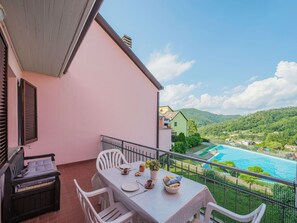 A balcony with a table set for two, a chair, and a bench.