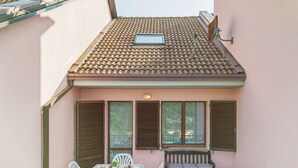 Ein Balkon mit Tisch und Stühlen, einem kleinen Fenster und einem Ziegeldach.