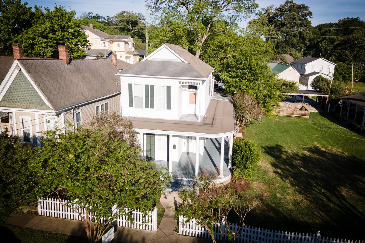A two-story house with a covered porch and a fenced yard.