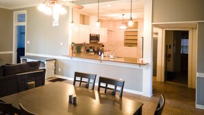 A modern kitchen with white cabinets, a central island, and pendant lighting. - Arlington House (Natchez)