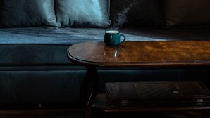 En trævæg med et vindue, en sofa med puder og et bord med en kop.