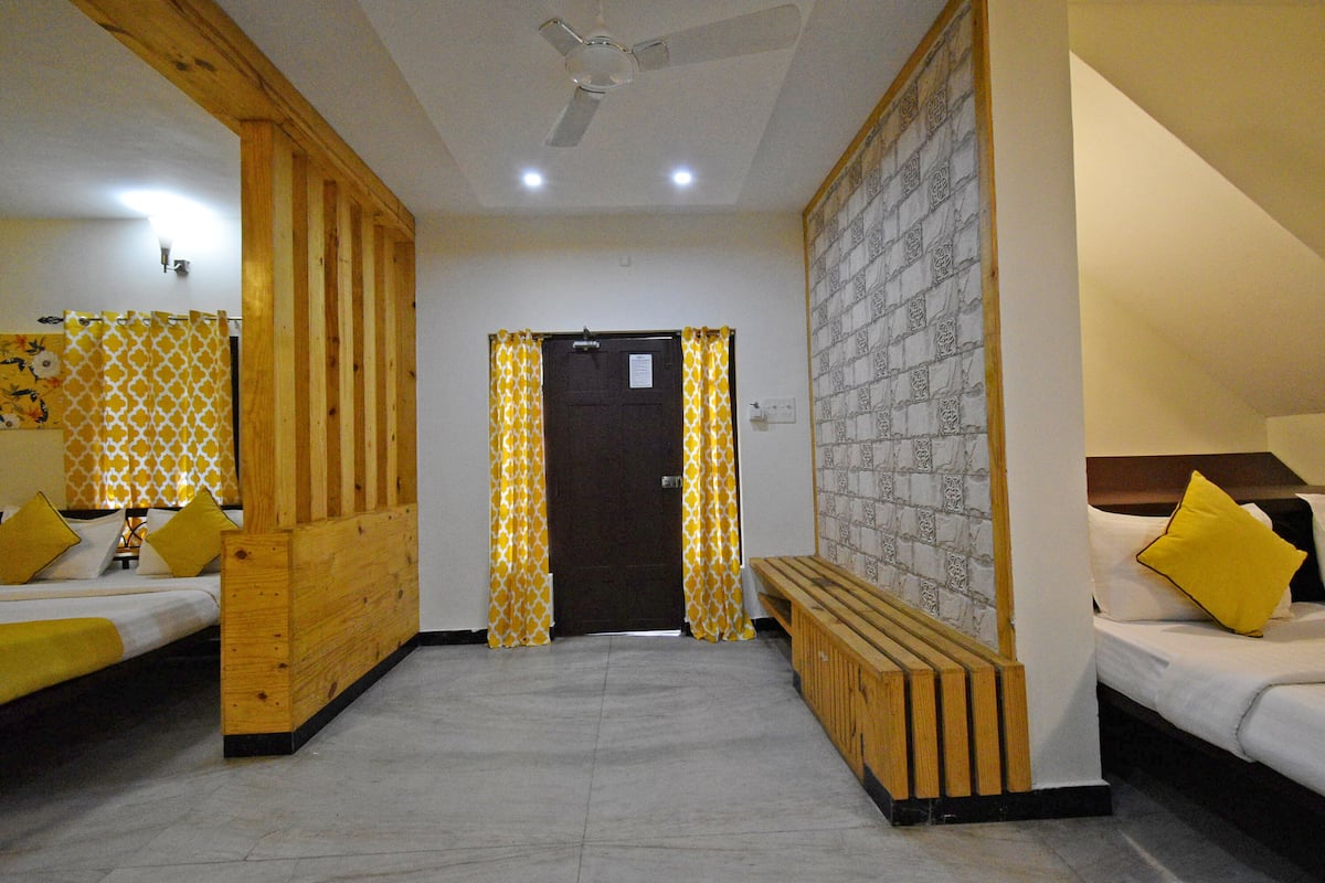 Habitación de hotel con dos camas, un banco de madera, un ventilador de techo y papel tapiz estampado.