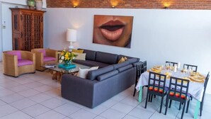 Un salon comprenant un canapé, deux fauteuils, une table basse et une table à manger mise pour le repas.