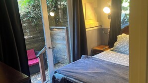 Een slaapkamer met een bed, een nachtkastje met een lamp, een raam met gordijnen en uitzicht op de omgeving.