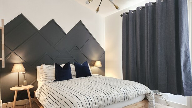 A modern bedroom with a bed, two bedside lamps, a wall-mounted light fixture, and a window with curtains. - The overlook stay | Free parking｜12 (Harvie Heights)