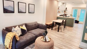 A modern living room with a brown sofa, a small round table, and a kitchen area in the background. - The overlook stay | Free parking｜12 (Harvie Heights)
