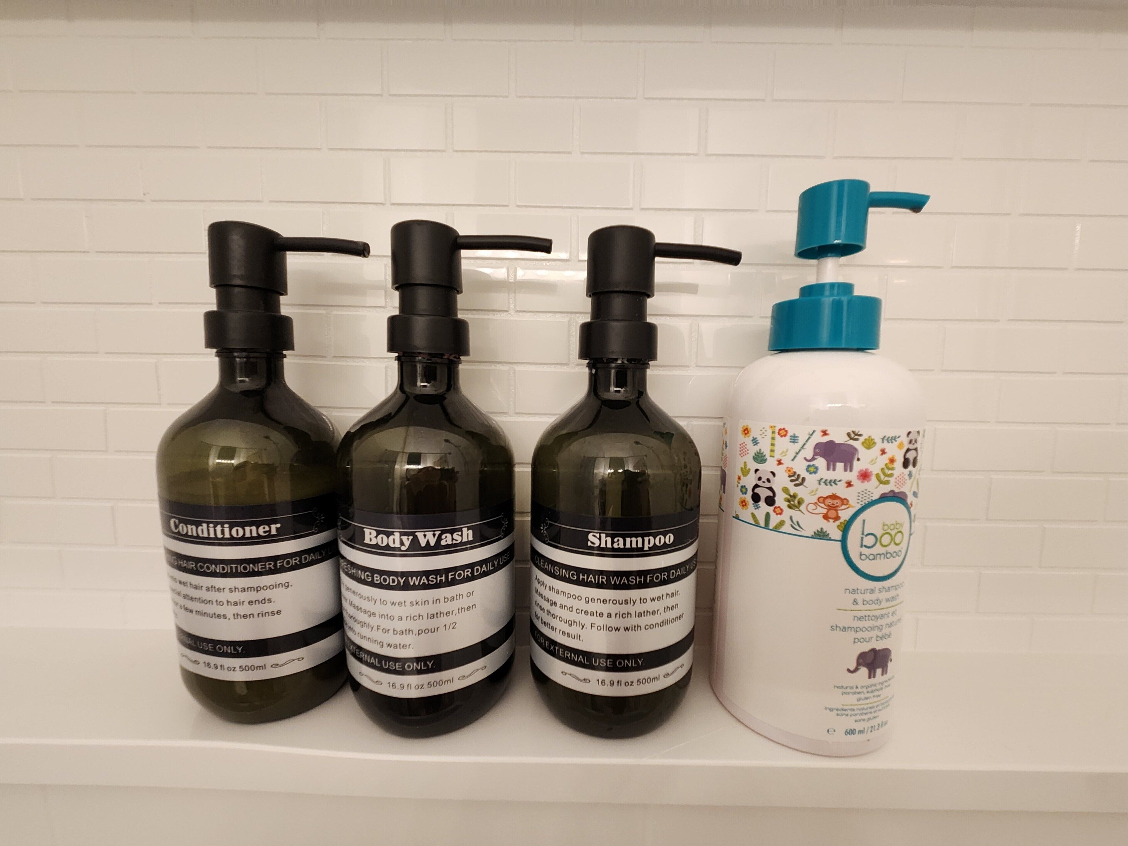 Três frascos de produtos para cabelo e um frasco de shampoo para bebé numa estante branca.