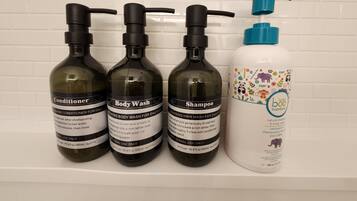 Três frascos de produtos para cabelo e um frasco de shampoo para bebé numa estante branca.
