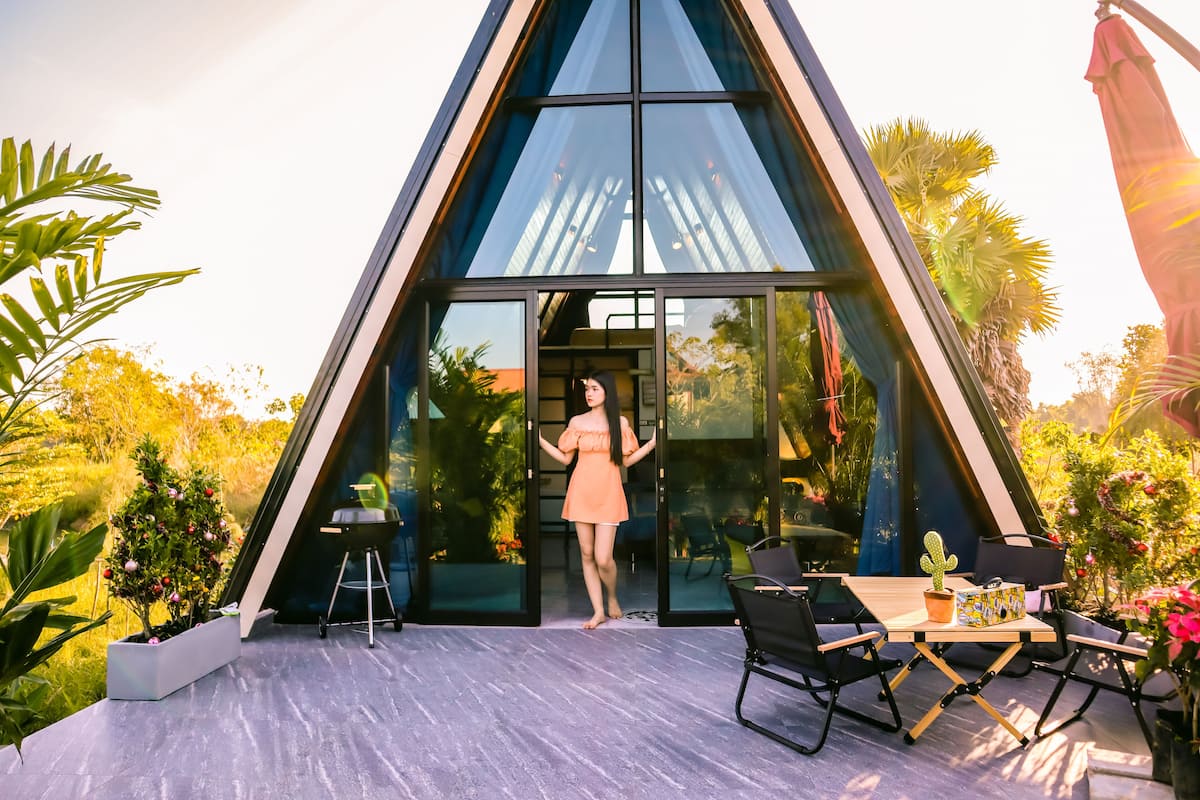 Une structure moderne en verre, de forme triangulaire, dotée d’un patio, d’un espace extérieur aménagé pour s’asseoir et d’une petite plante succulente.