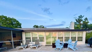 A covered patio with outdoor furniture, a grill, and a view of the surrounding landscape. - Charming 4/3 Lakehouse W/ Pool (Tampa)