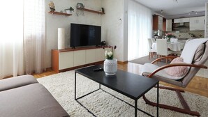 Olohuone, jossa on televisio, sohva, sohvapöytä sekä ruokailutila tuoleineen ja pöytineen.