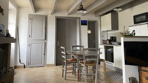 Une cuisine avec des meubles blancs, une table à manger avec des chaises et un plafond en bois.