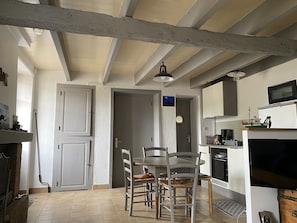 Una cocina con armarios blancos, una mesa de comedor con sillas y techo de madera.