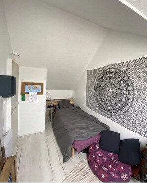 Cozy attic retreat with a bed, desk, and world map.