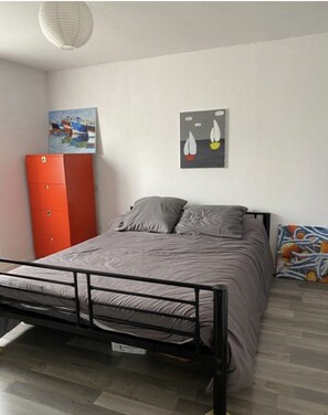 Un dormitorio con cama, armario y obras de arte en las paredes.
