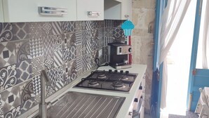 A kitchen with patterned tiles, a gas stove, and a coffee maker. - New LOFT on Ortigia waterfront for max 3 guests (siracusa)