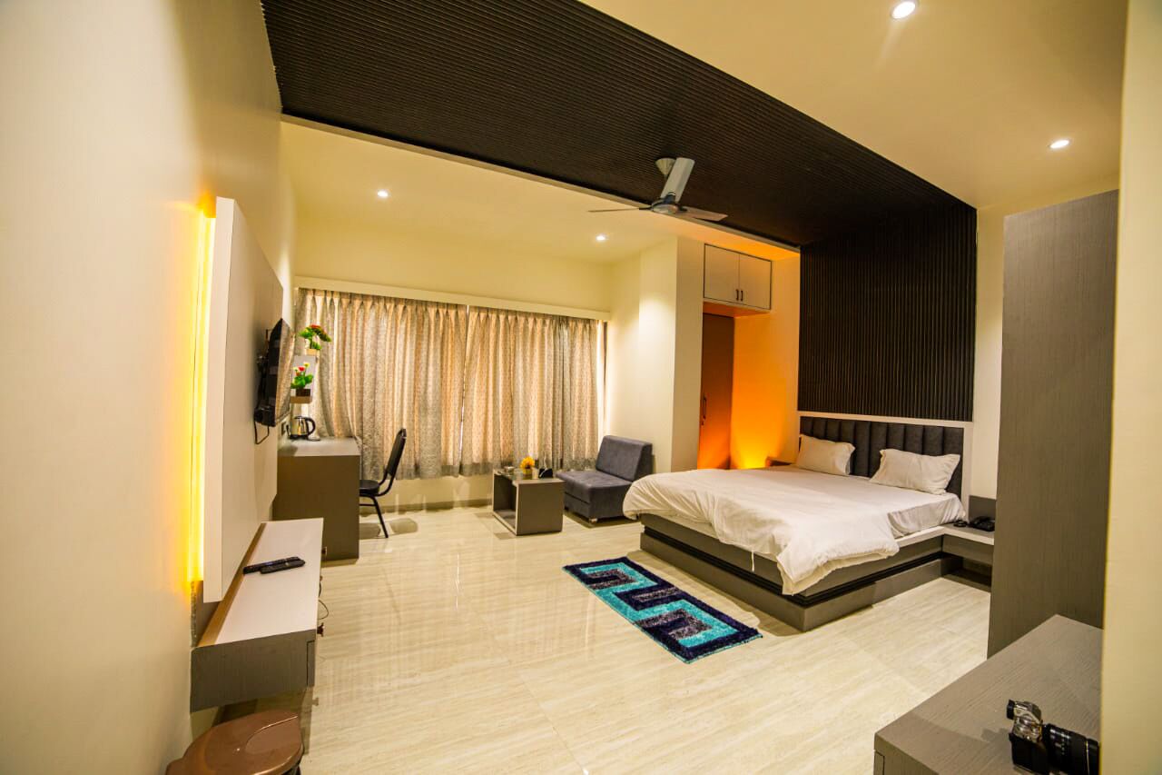 Una habitación de hotel moderna con una cama grande, un escritorio, una silla, una mesita y un ventilador de techo.